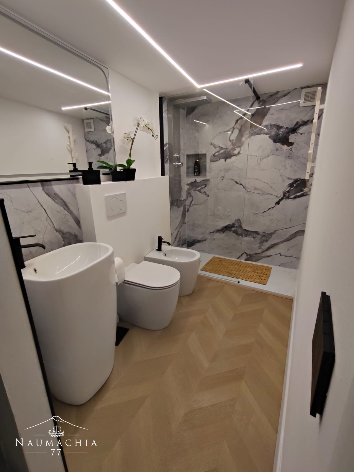 Bagno con doccia in marmo e sanitari sospesi