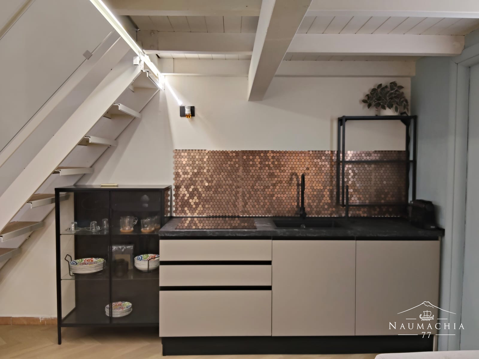 Cucina con rivestimento esagonale in rame sotto le scale